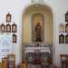 Di fronte a noi osserviamo una delle decorazioni sopravvissute: una statua di Santa Lucia posta su un altare in marmo, racchiusa in una nicchia in pietra e circondata da cornicette in legno con le tappe della Via crucis